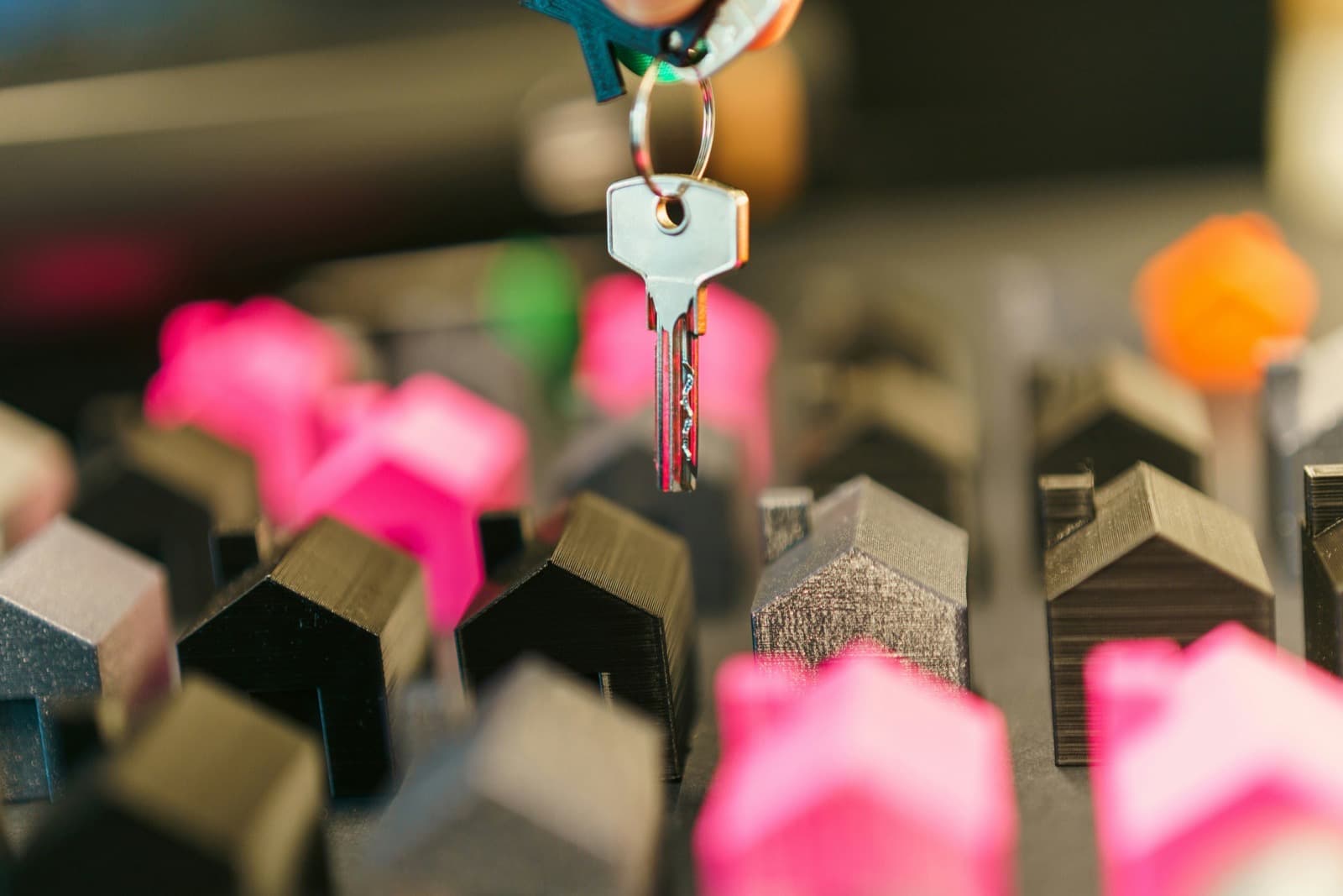 A house key hanging above a row of small model houses